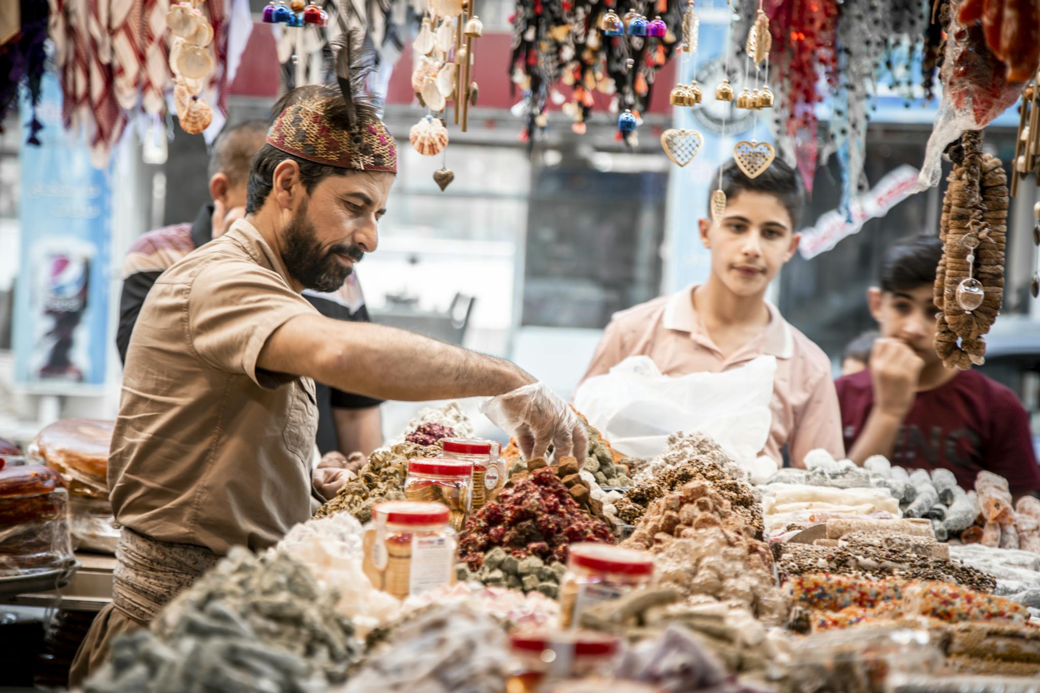 A vibrant street market scene with a vendor selling assorted goods to customers. Candid interaction and colorful display.