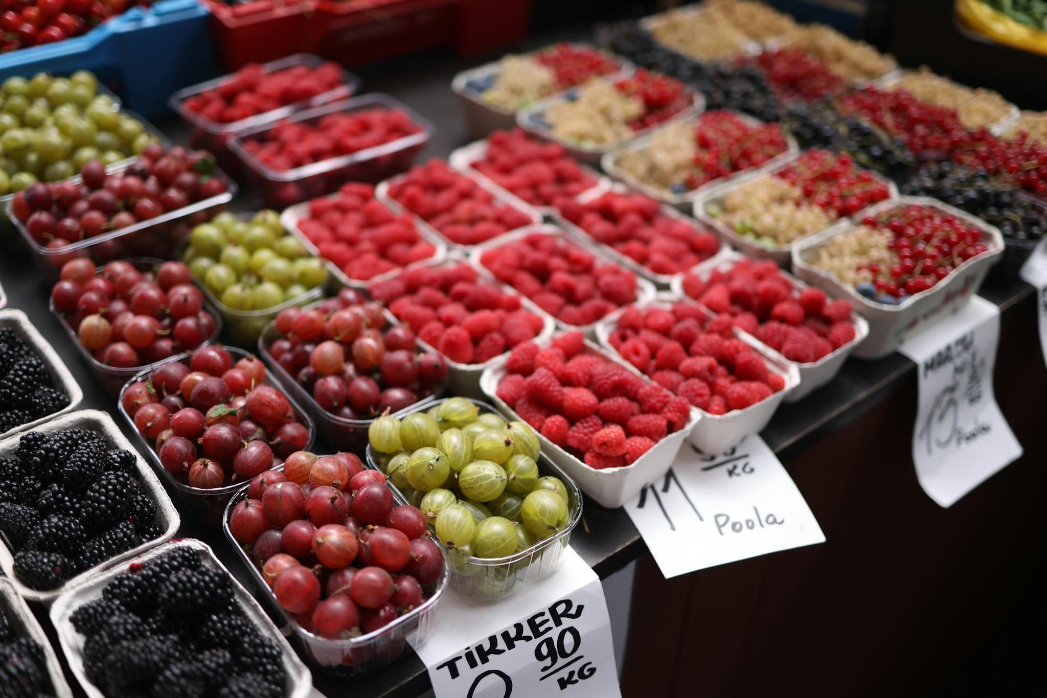 Vibrant assortment of fresh berries displayed in containers at a bustling market.